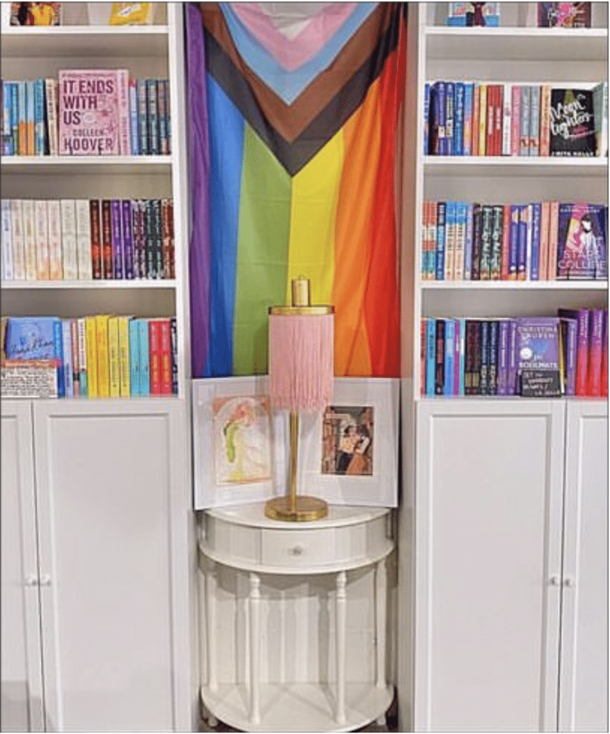 A Pride Flag surrounded by bookshelves.